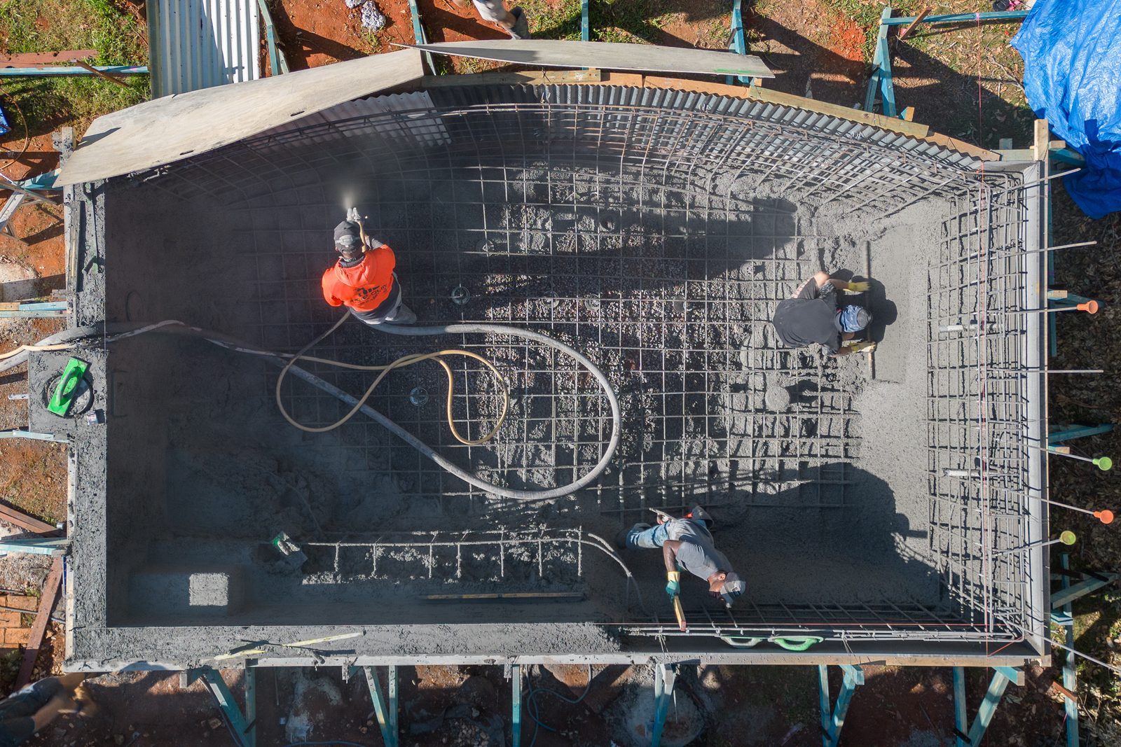 Overhead view of a pool shell being sprayed and shaped by the Pumpd crew