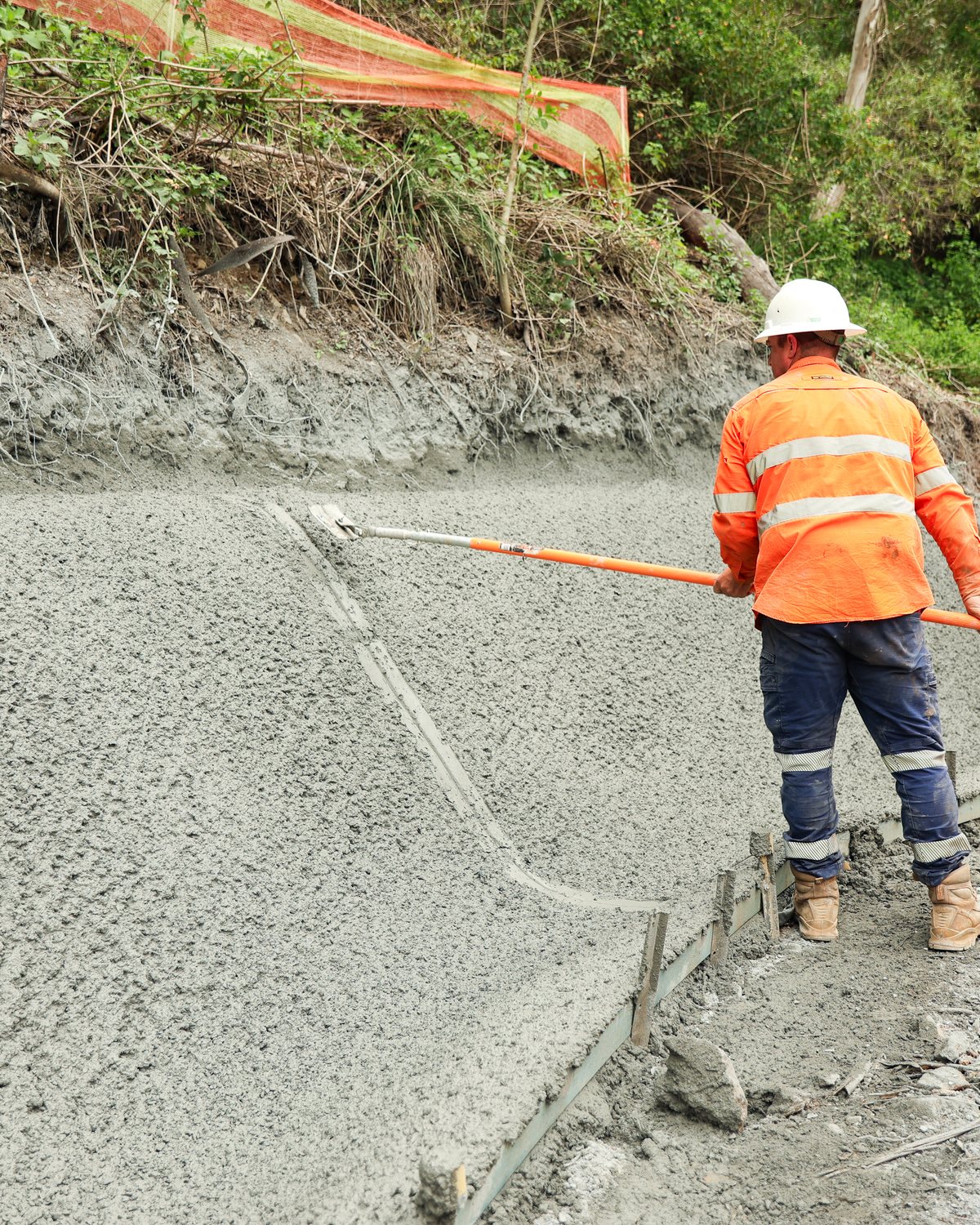 A crew finishing a sprayed slope beside a haul road