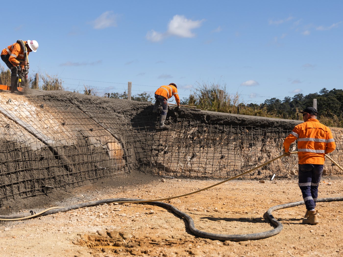 A Pumpd crew running hose to a meshed batter on a civil site